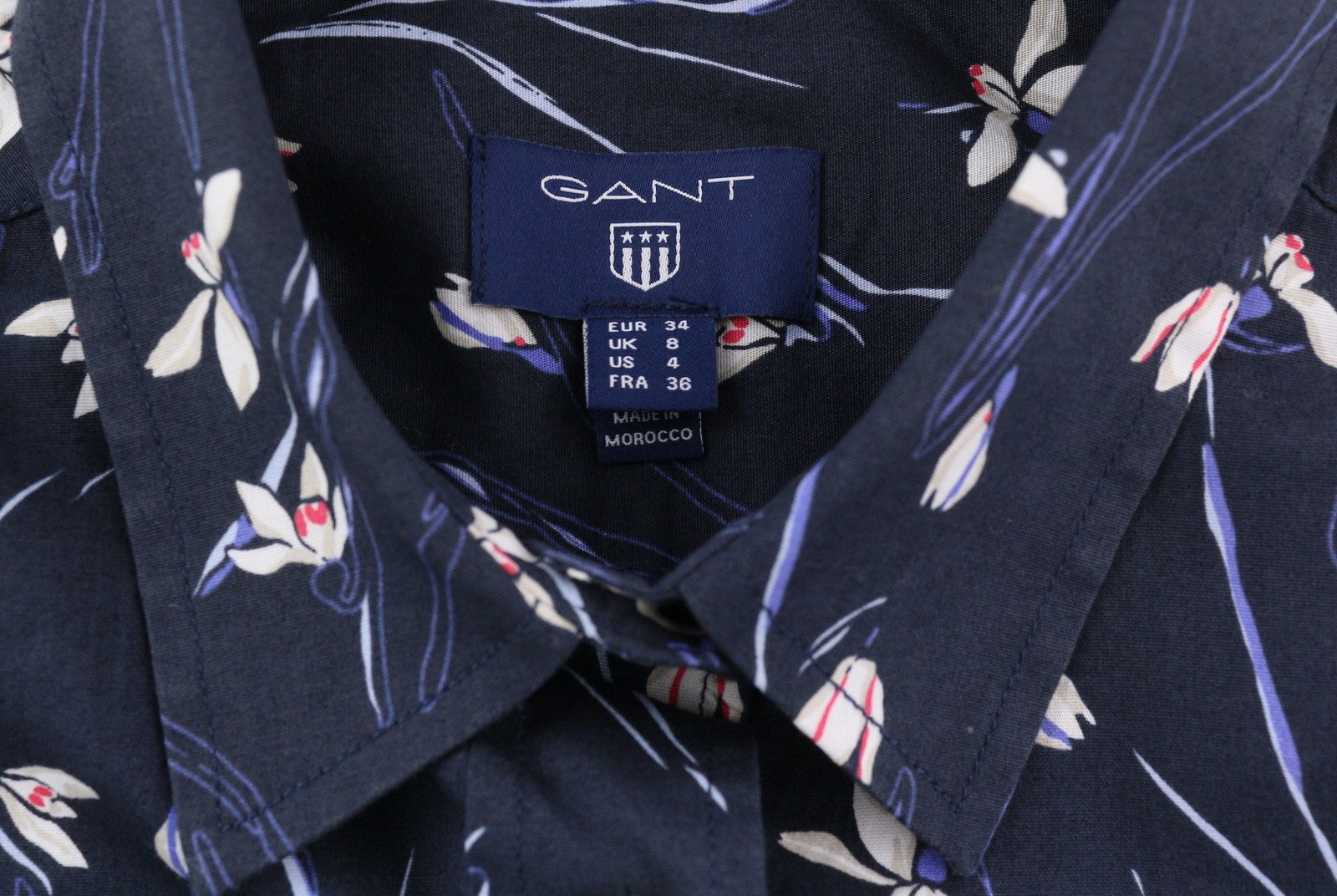 GANT „Snowdrop“ moteriški marškinėliai, 34 dydžio, tamsiai mėlyni, gėlėto rašto, su sagomis ir platėjančia apykakle. 